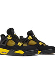 Pair of Jordan 4 Retro Thunder (2023) in black and yellow
