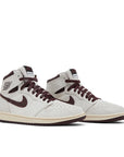 A pair of Air Jordan 1 A Ma Maniere is in a cream and maroon colourway