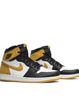 A pair of Nike Air Jordan 1 High Yellow Ochre Michael Jordans in white, black and ochre