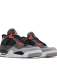 A pair of Nike Air Jordan 4 retro infared basketball shoes in a white, black and grey colourway.