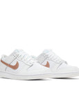 A pair of the Nike dunk low grade school sneaker in white and pink