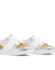 A pair of the Nike SB Dunk Low Heirloom womens shoe in white and gold