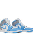 A pair of Jordan 1 Mid University Blue Grey sneakers