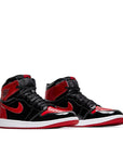 A pair of Nike Air Jordan 1 High OG Patent Bred basketball shoes in black and red