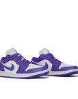 A pair of women's Nike Air Jordan 1 Low sneakers in white and purple