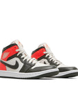 A pair of Jordan 1 Mid 'light Orewood Brown' is in a black and red colourway