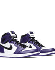 A pair of Nike Air Jordan 1 Retro High Court Purple White basketball shoes in white and purple