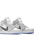 A pair of Nike Air Jordan 1 Retro High Dior sneakers in grey and white