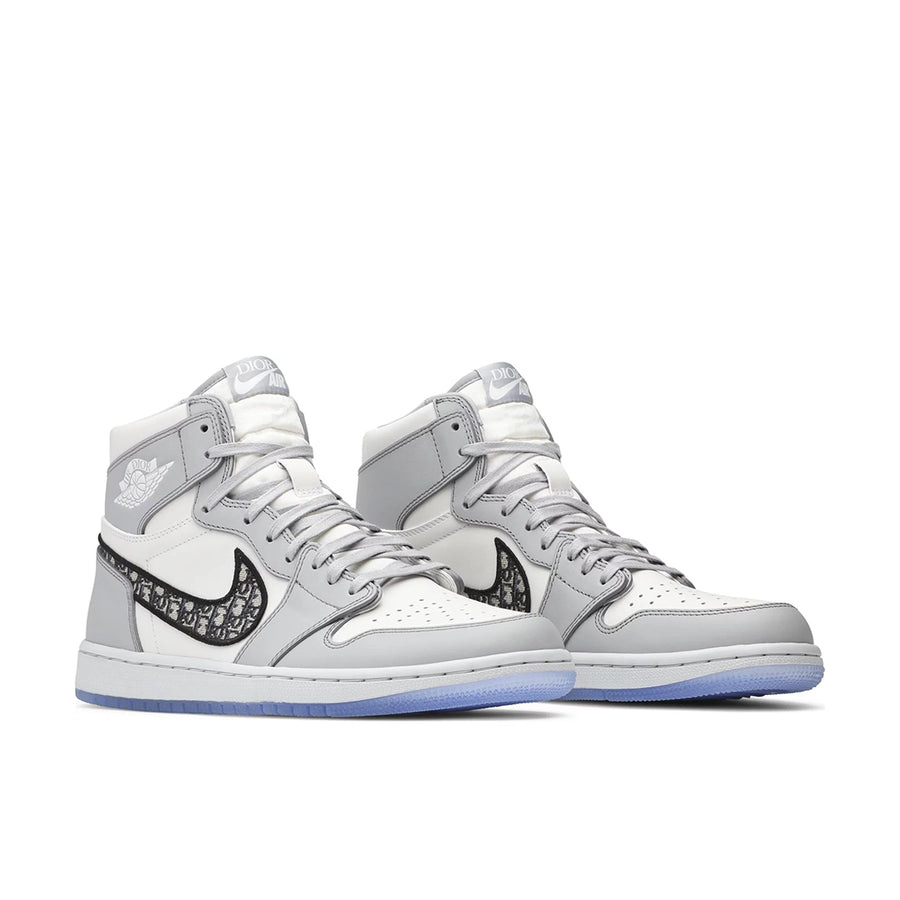 A pair of Nike Air Jordan 1 Retro High Dior sneakers in grey and white