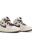 A pair of Air Jordan 1 A Ma Maniere is in a cream and maroon colourway
