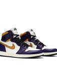 A pair of Nike Air Jordan 1 Retro High OG Defiant SB LA to Chicago basketball shoes in purple and gold