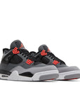 A pair of Nike Air Jordan 4 retro infared basketball shoes in a  white, black and grey colourway.