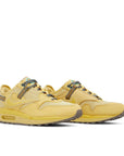 A pair of the of the Nike air max travis scott in saturn gold colour