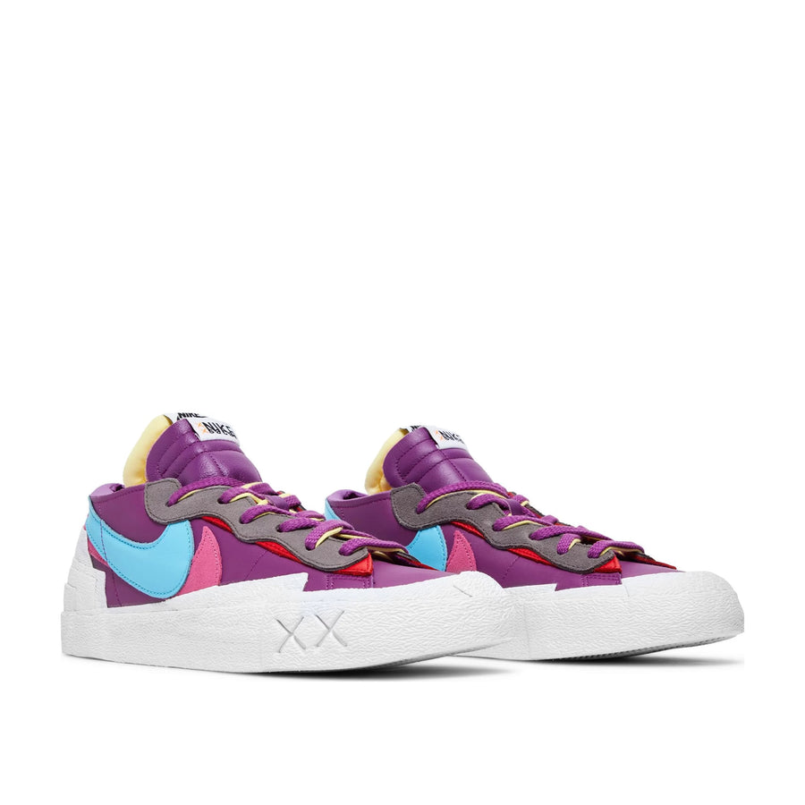 A pair of Nike Blazer Low Sacai KAWS Purple Dusk skateboard shoe in purple and white