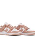 A pair of the womens Nike dunk lows in a white peach "rose whisper" colour