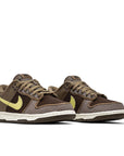 A pair of the Nike dunk low sp undefeated canteen in brown and lemon