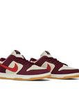 A pair of the Nike sb dunk low pro skate like a girl skating shoes in burgundy and cream